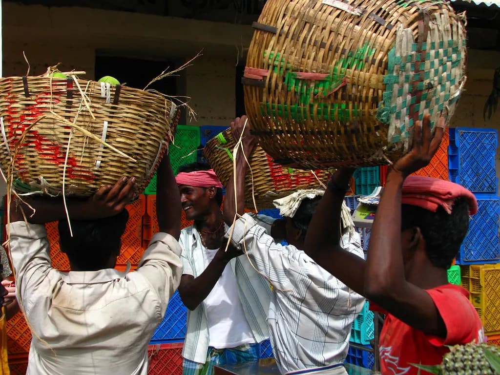 Porters carrying large baskets of produce on their heads at Koyambedu wholesale market, Chennai