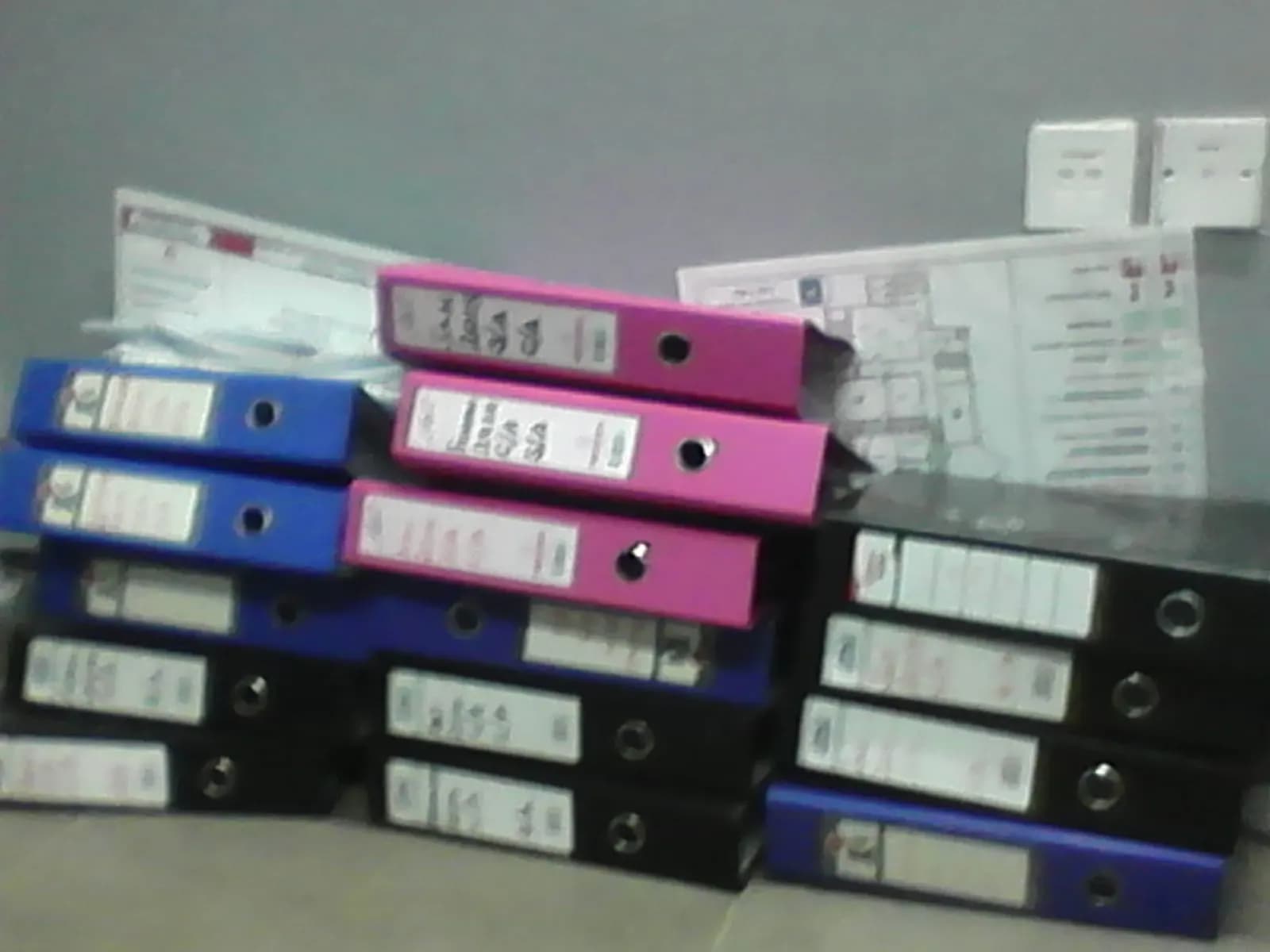 Stacked lever-arch office files with printed labels on their spines