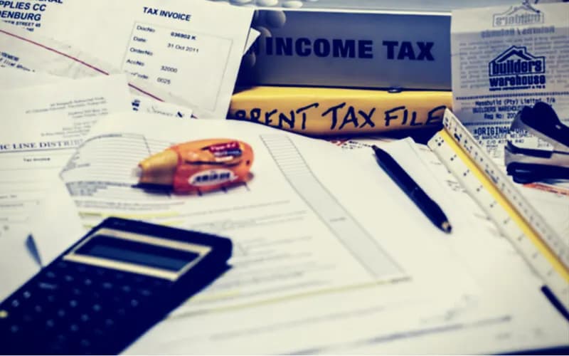 Tax invoices, a calculator, a pen and tax files spread across a desk