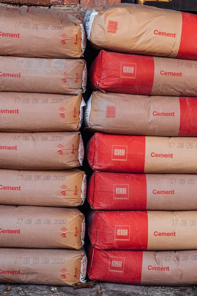 Close-up of cement bags stacked in two columns, brown paper bags on the left and red bags on the right