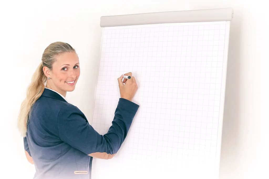 A consultant in a blazer writing on a blank grid flip chart during a session