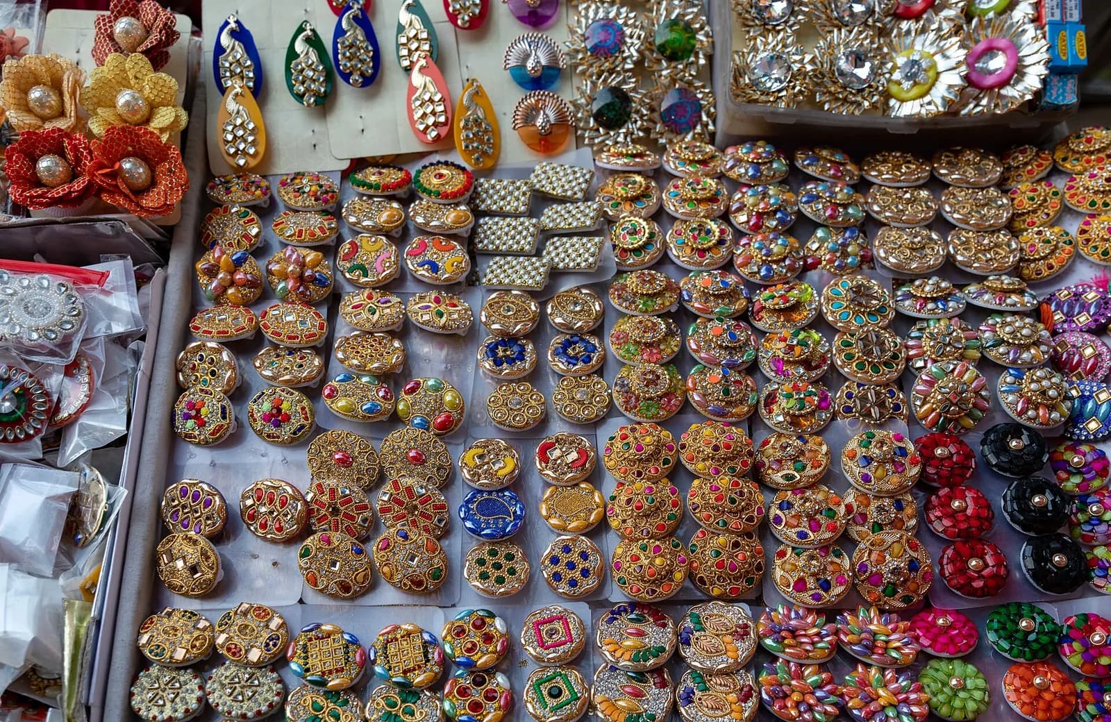 Rows of colourful kundan-style rings and earrings arranged on a display tray in a Jaipur jewellery shop