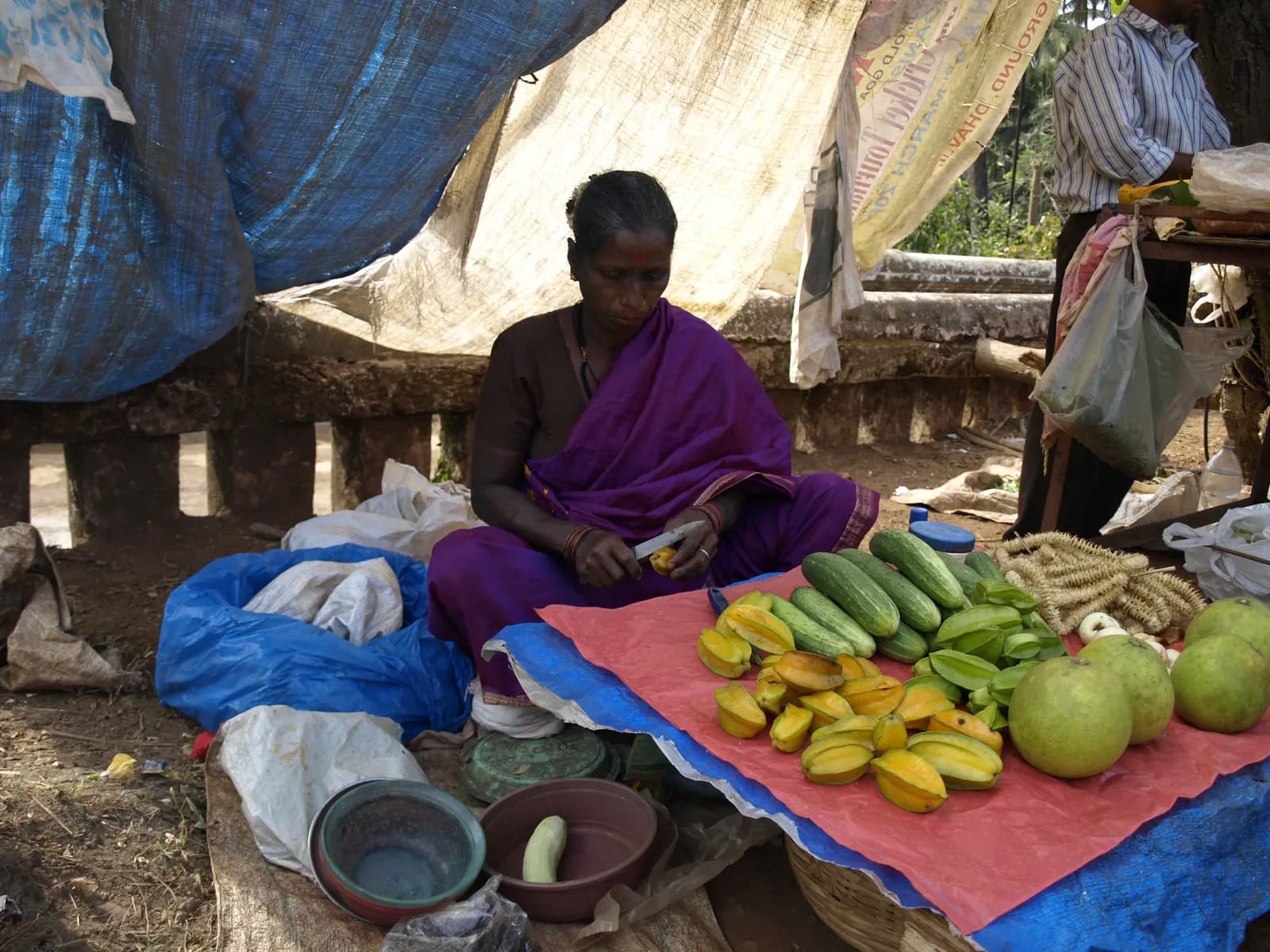 A vegetable vendor in a Goa market checking her mobile phone beside her produce
