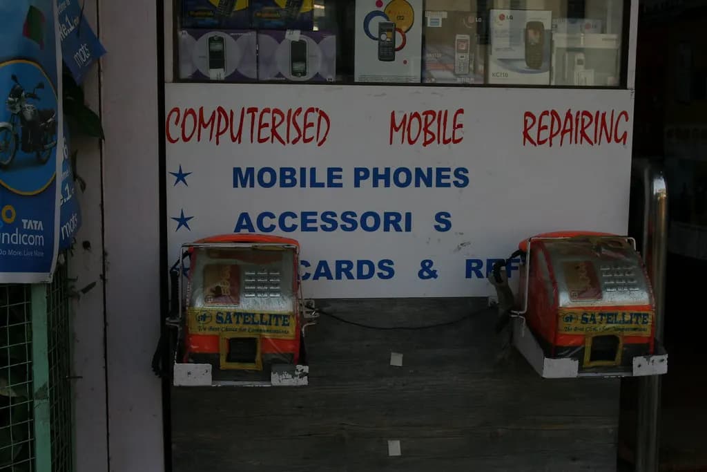 A small shopfront sign advertising computerised mobile phone repairing and accessories