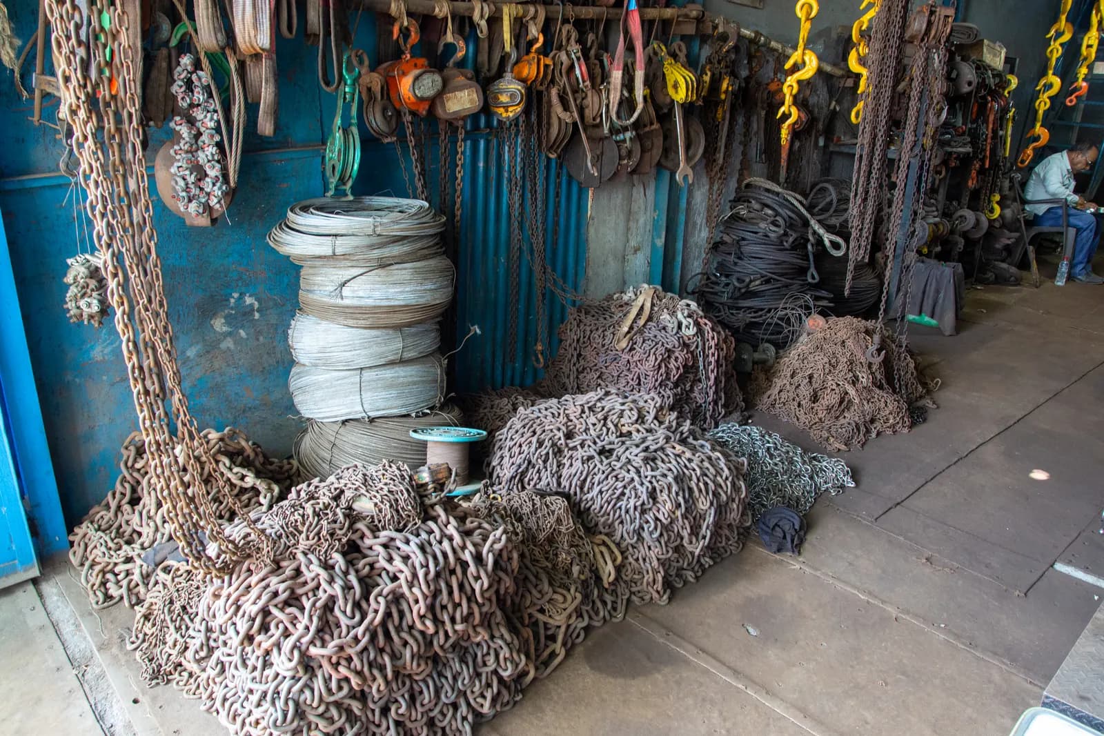 Heaps of steel chains, coils of wire rope and lifting hooks stacked in a trader's godown