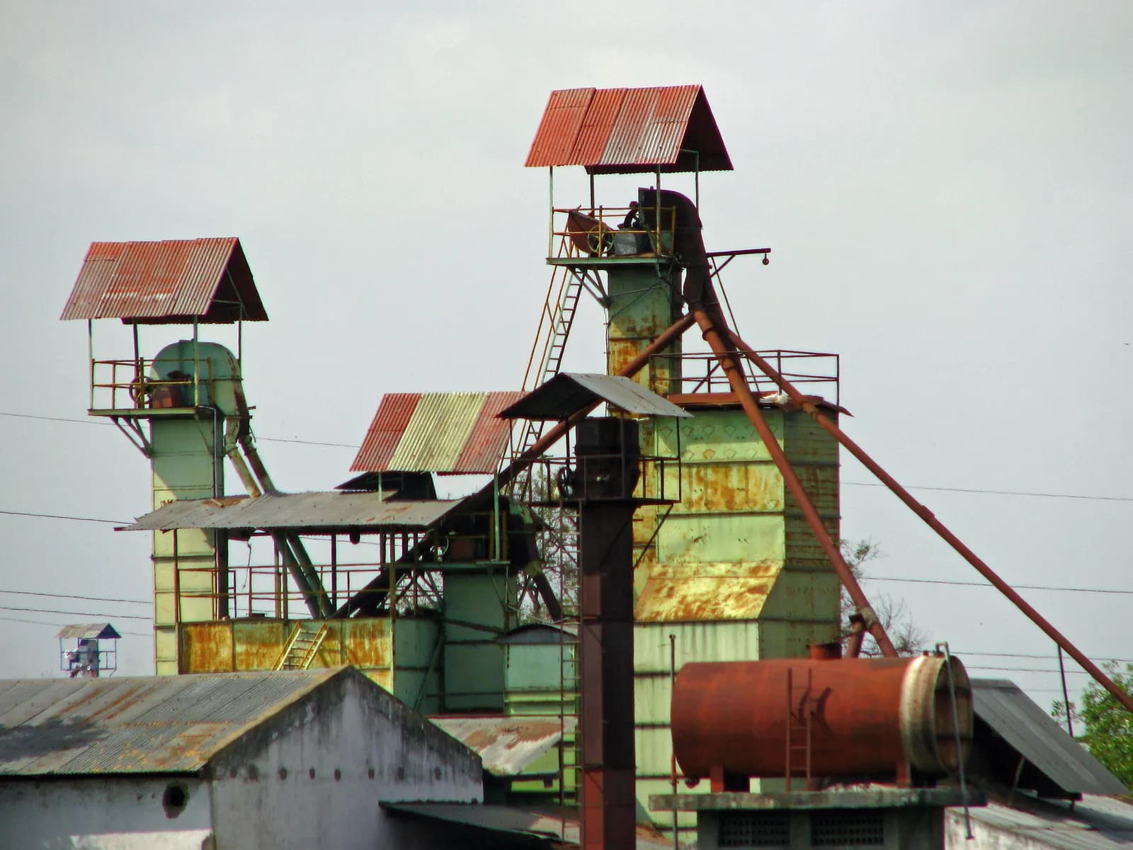 Weathered elevators, ducts and tin-roofed sheds of a small rice mill in rural India