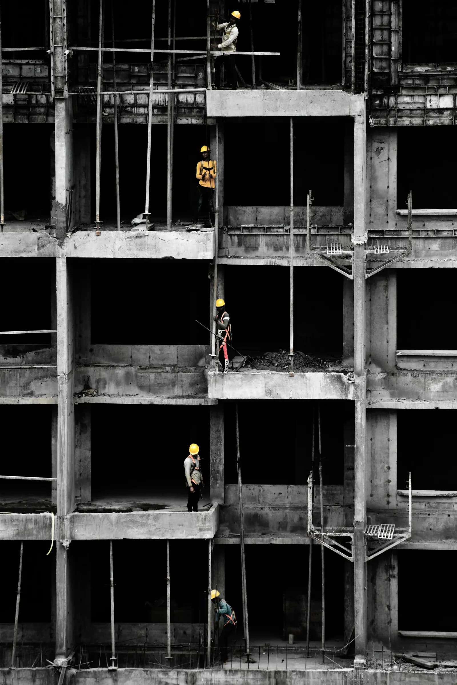 Construction workers standing on the concrete roof of a building under construction in India, in black and white