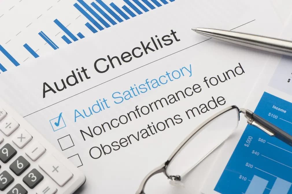 A printed audit checklist on a desk with a pen