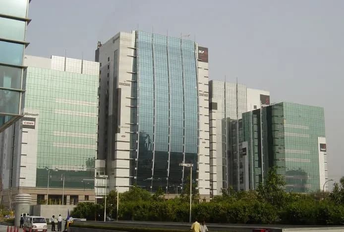 Glass-fronted office towers in a Gurgaon business district under a hazy sky