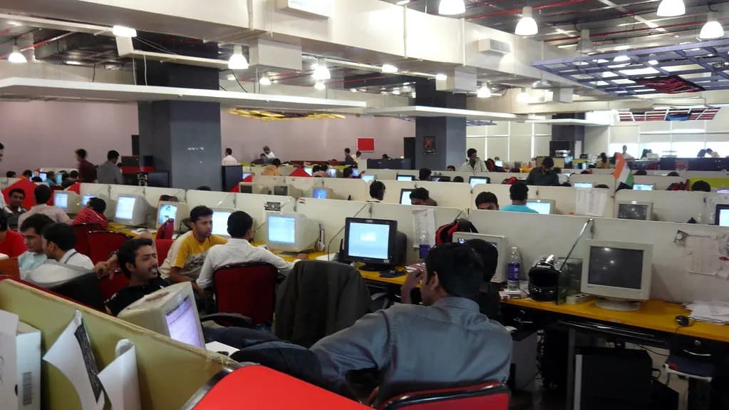 Rows of computer workstations with staff at work on an open-plan IT office floor in India