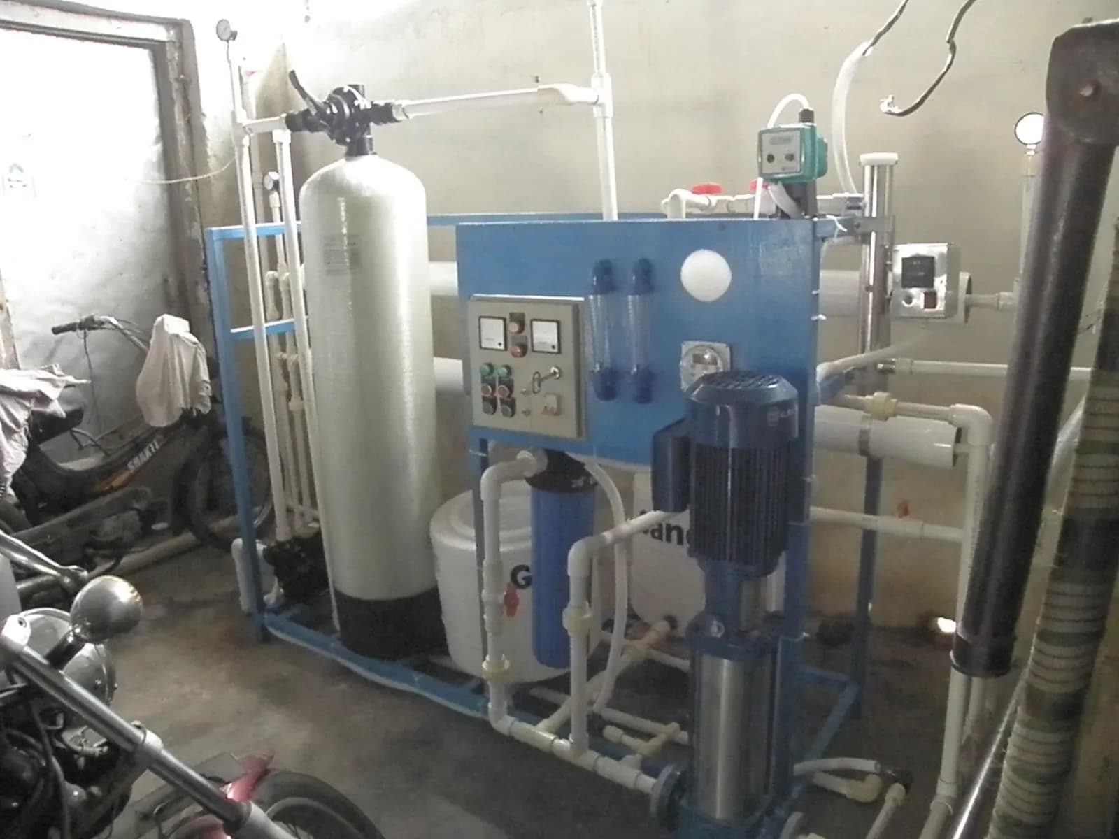 A commercial reverse osmosis unit with filter housings, pressure vessels, pump and control panel mounted on a steel frame