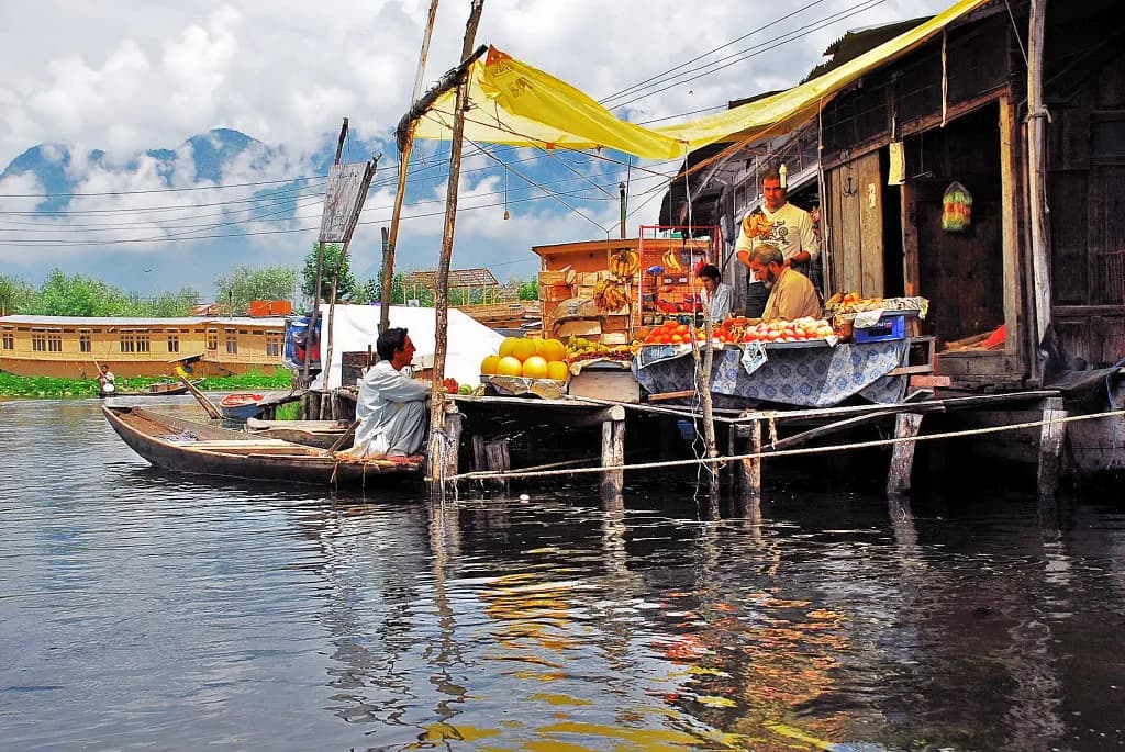 A grocery and fruit shop on stilts on Dal Lake, Srinagar, with a shikara moored alongside