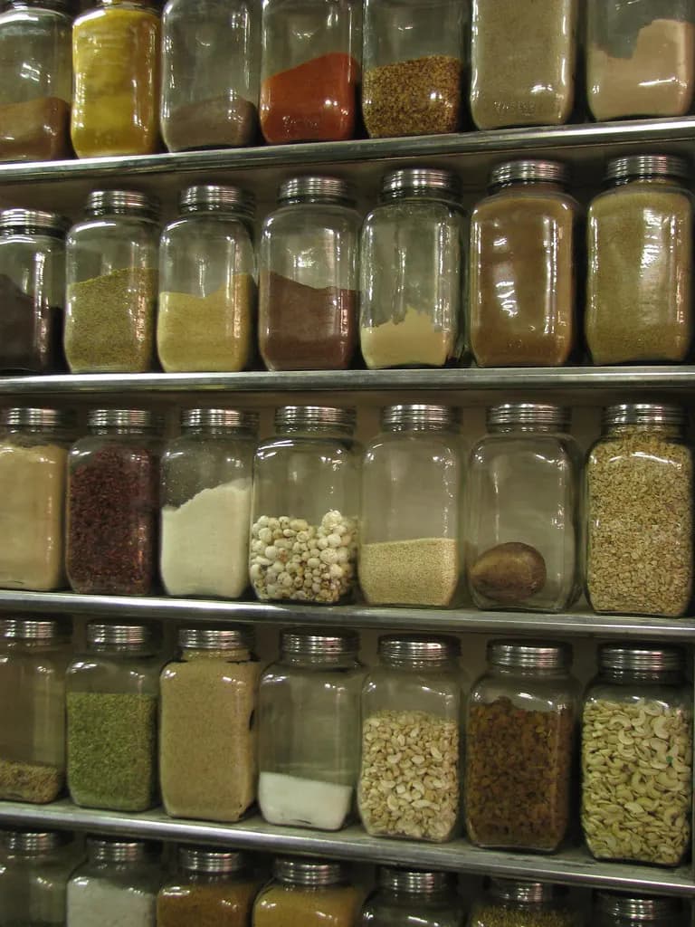 Glass jars of spices and dry fruits stacked on shelves in a shop at New Market, Kolkata