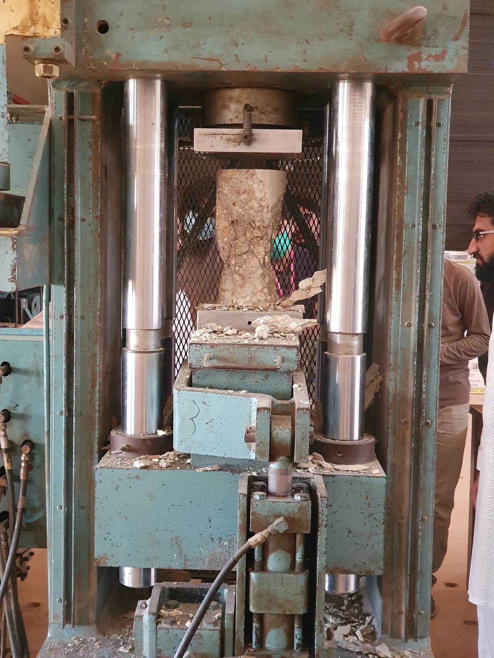 A concrete cylinder being crushed in a universal testing machine during a compression test