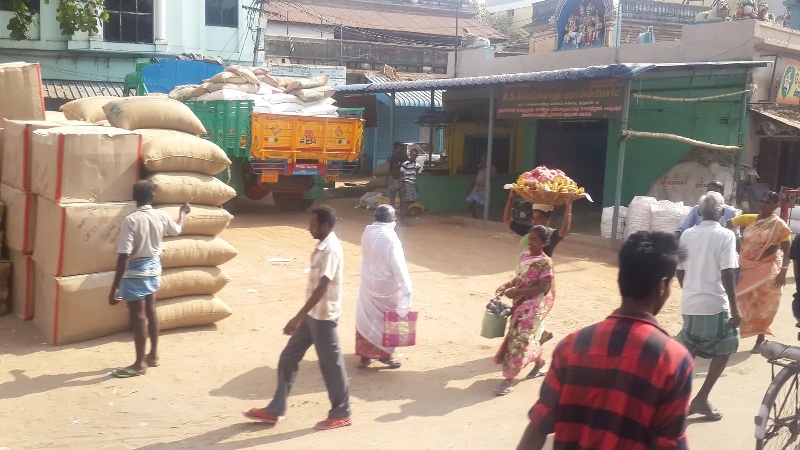 Sacks of spices piled outside a wholesale spice mandi in India as porters and buyers walk past