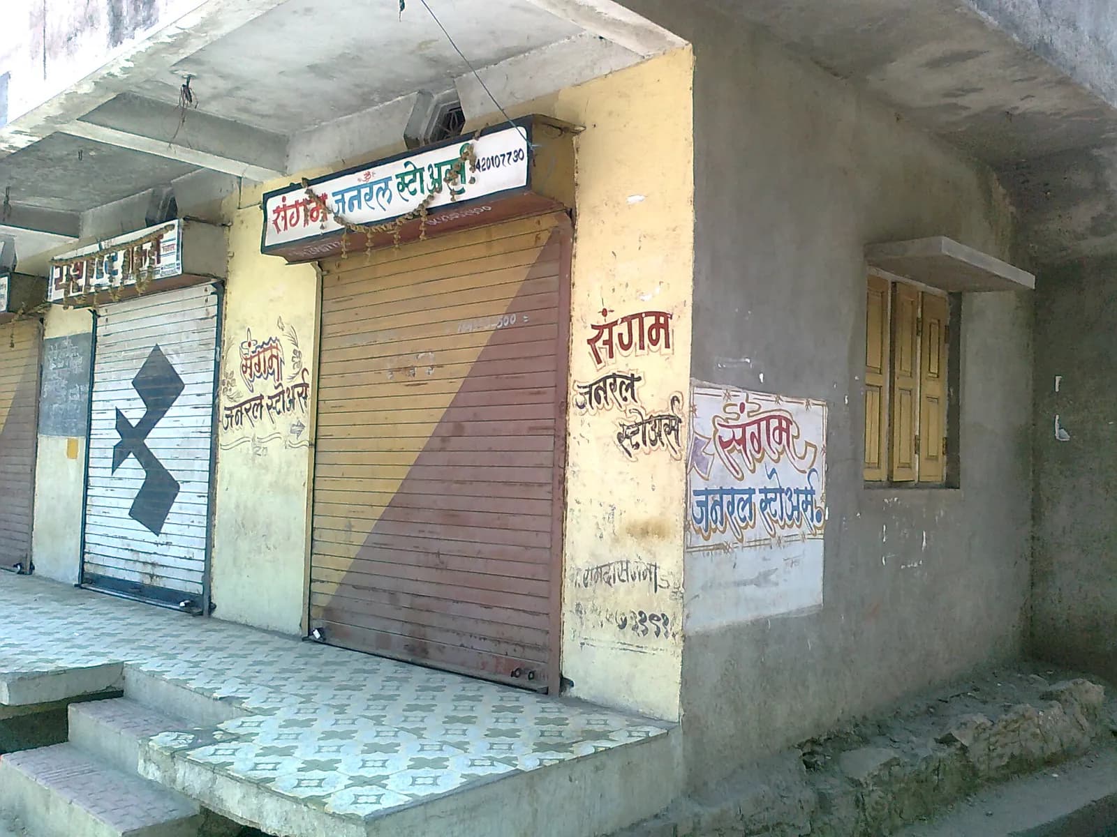 Shuttered fronts of a small general store and neighbouring shops in Chinawal village, Maharashtra, with hand-painted Marathi signs
