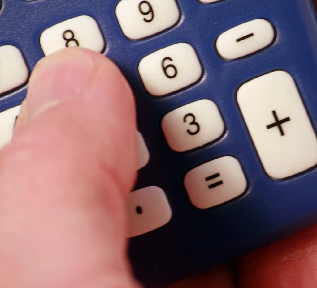 A finger pressing the keys of a blue pocket calculator