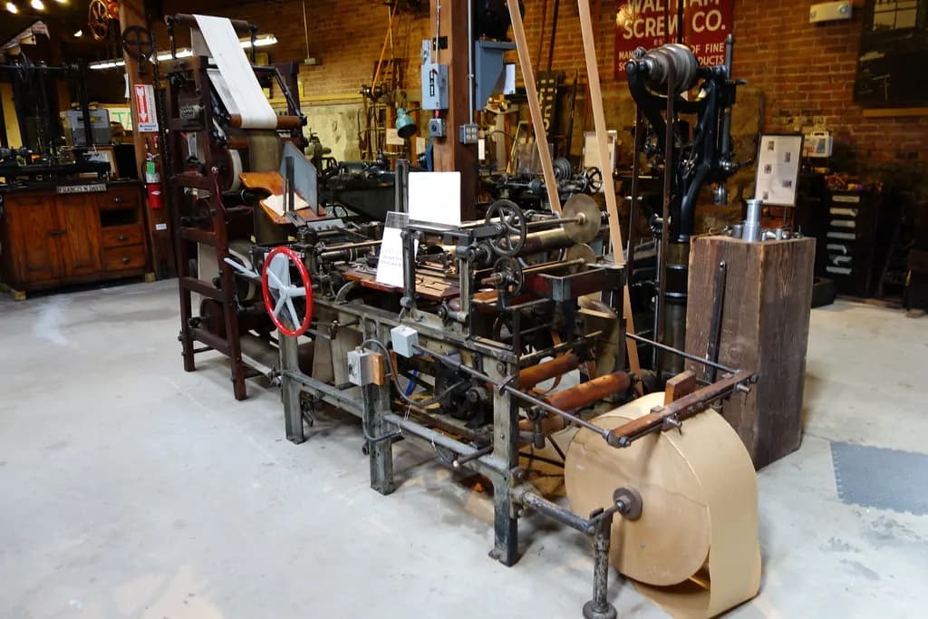 A roll-fed paper bag machine with a roll of brown kraft paper feeding into the folding and cutting section