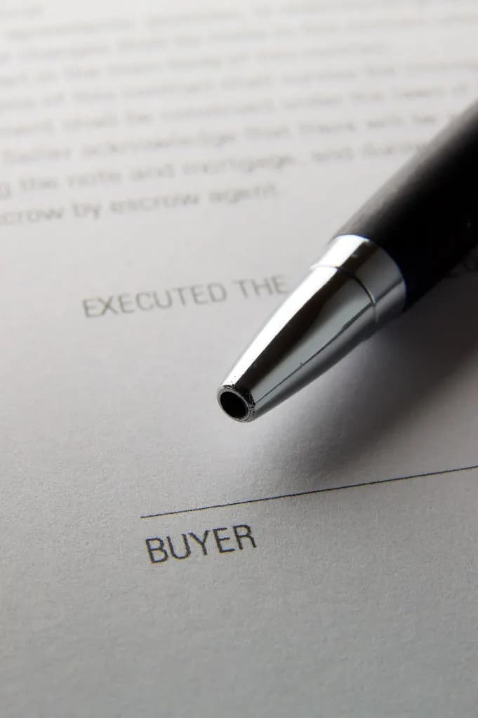 Close-up of a pen resting on a printed agreement above the signature line