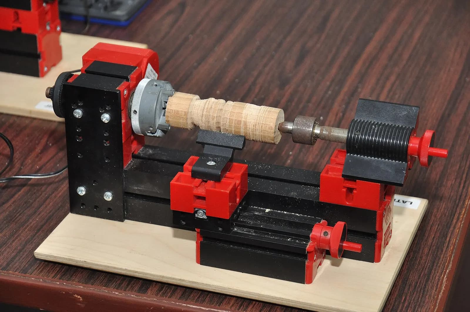 A small bench lathe turning a wooden workpiece on a workshop table