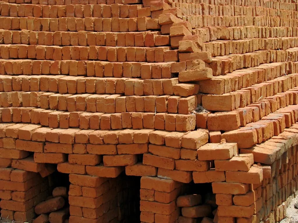 Freshly fired red bricks stacked in tiers at a rural brick kiln in India