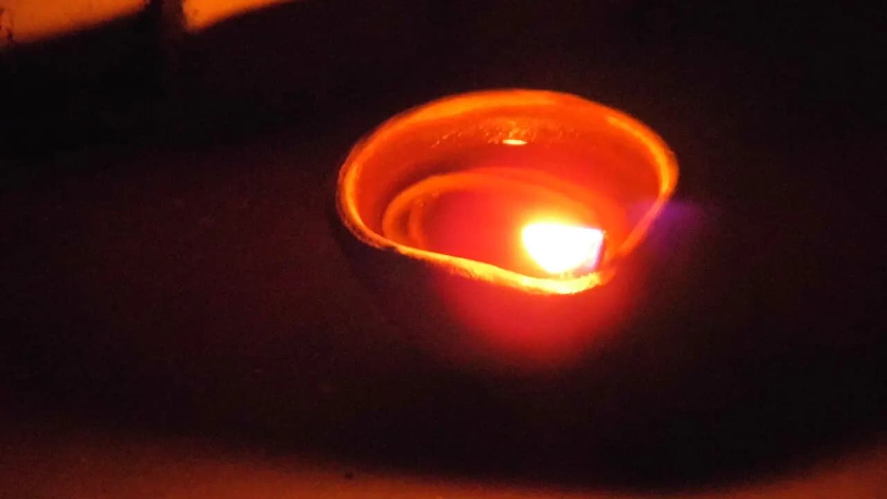 A lit clay diya oil lamp glowing in the dark