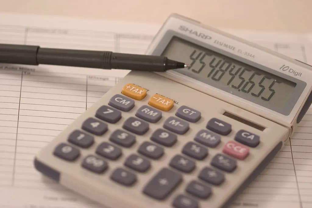 A calculator and pen resting on a printed ledger sheet