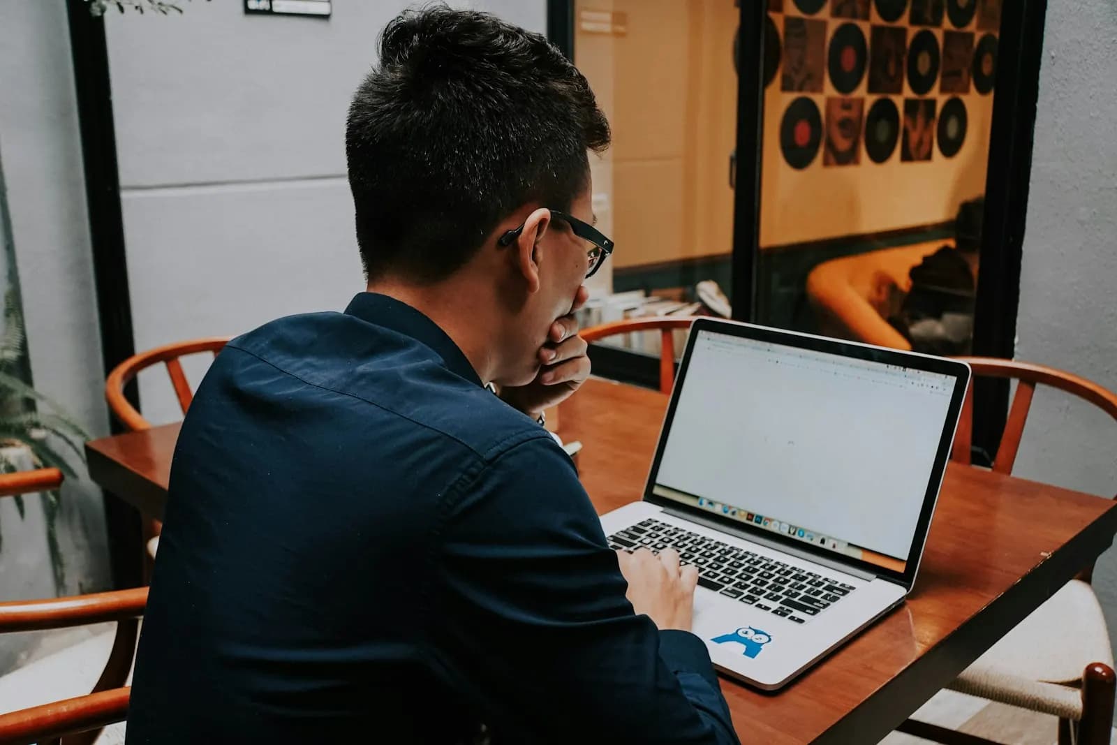 A young man at a table checking his account on a laptop