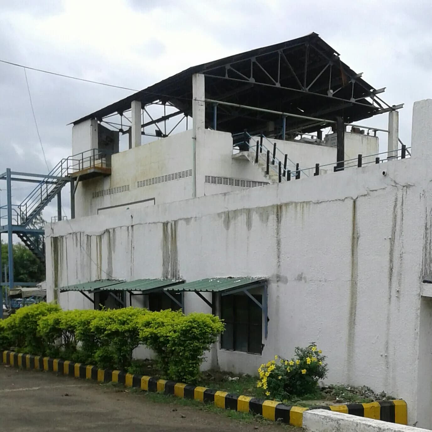 A white-walled effluent water treatment plant building with steel stairs and a raised platform at a MIDC industrial area in Maharashtra