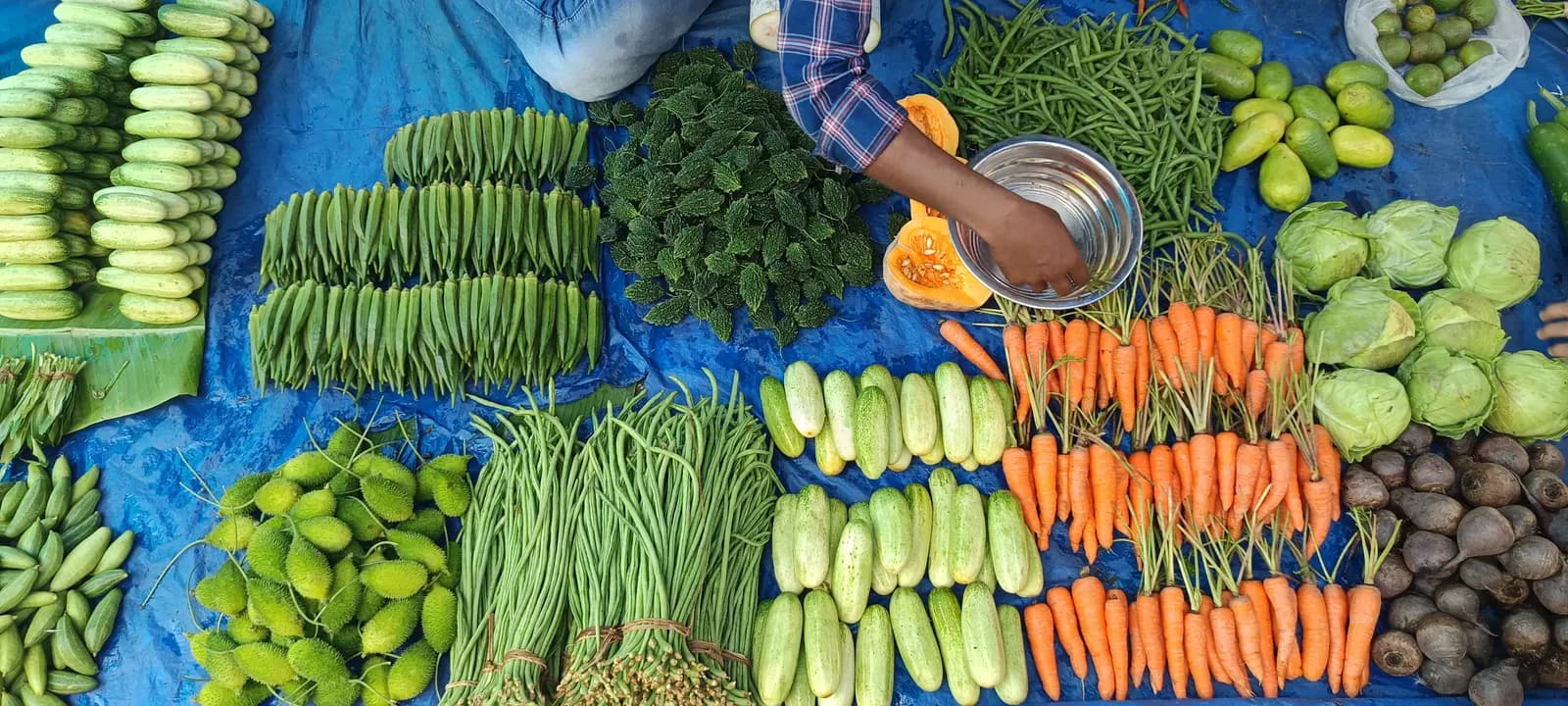 A vegetable vendor arranging produce at the Sunday Beltola market in Guwahati