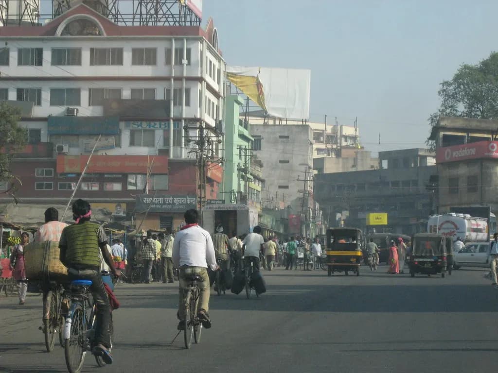 Cyclists, auto-rickshaws and shoppers on a busy main road lined with shops and offices in Jamshedpur