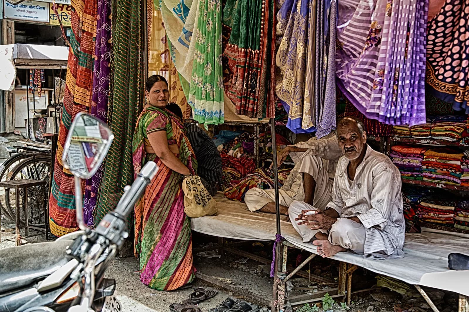 A trader sitting at a sari and cloth shop in Indore's cloth market while a customer stands at the counter