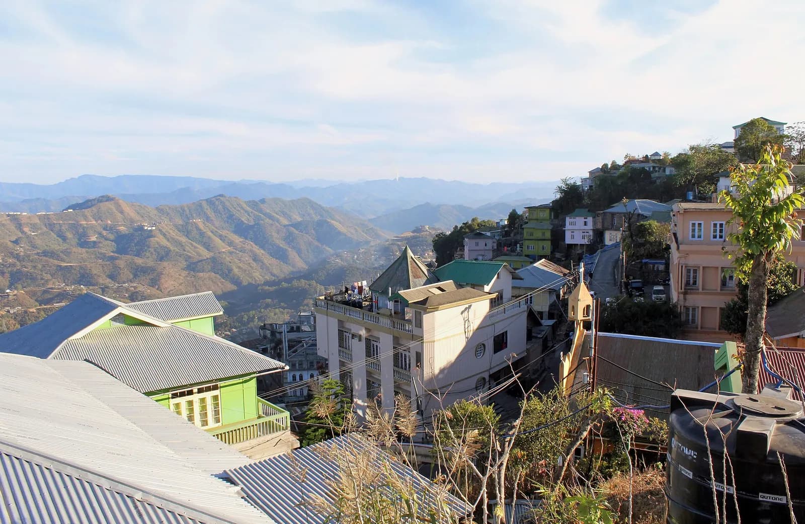 Houses with tin roofs on the ridge at Chaltlang, Aizawl, with forested hills behind