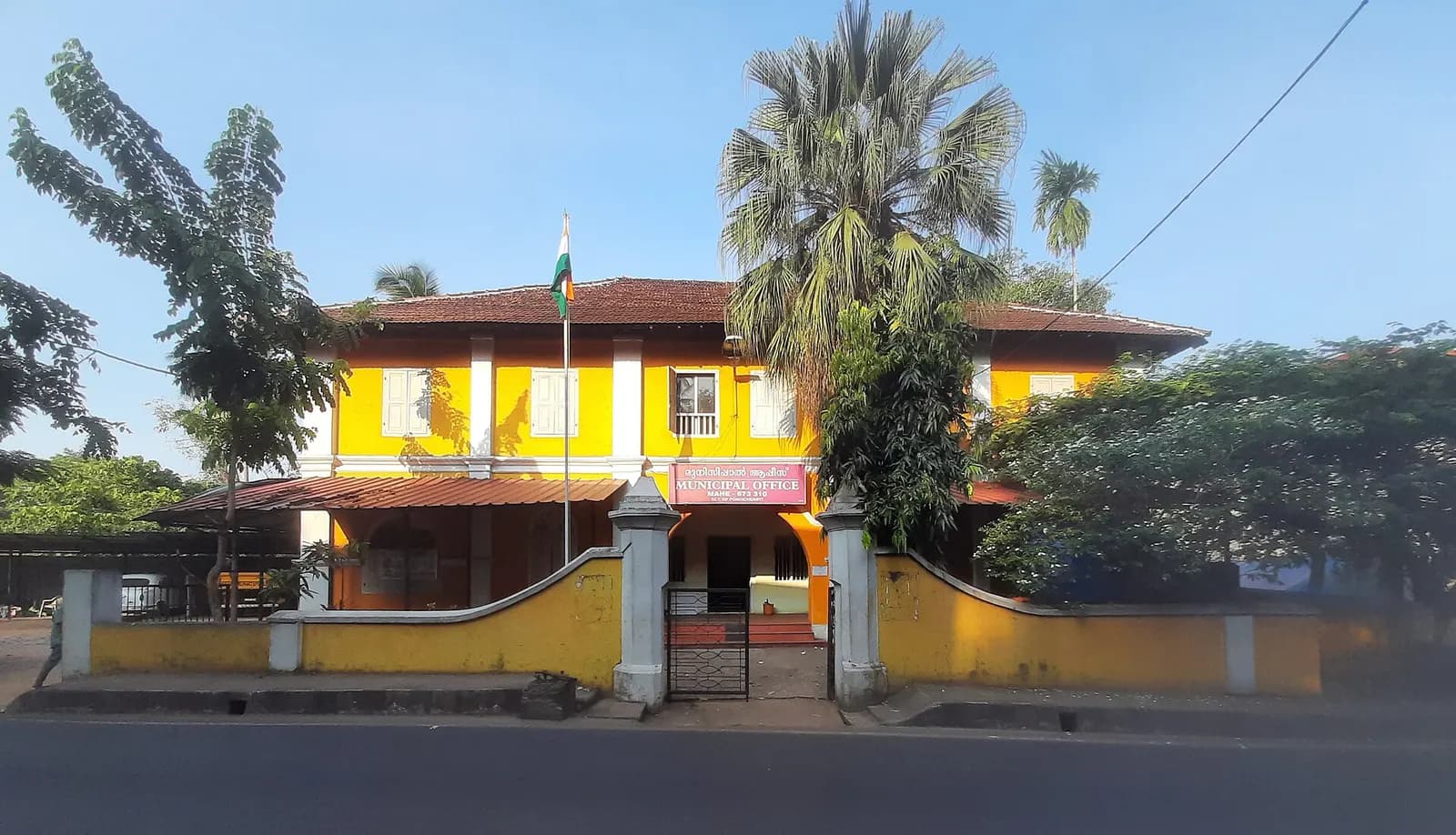 Yellow two-storey Mahe Municipal Office building behind a low wall and gate in Mahe, Puducherry