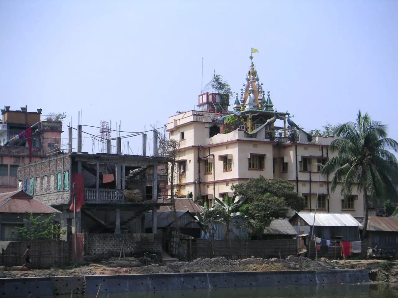 Multi-storey buildings and a temple tower beside a pond in Agartala, Tripura
