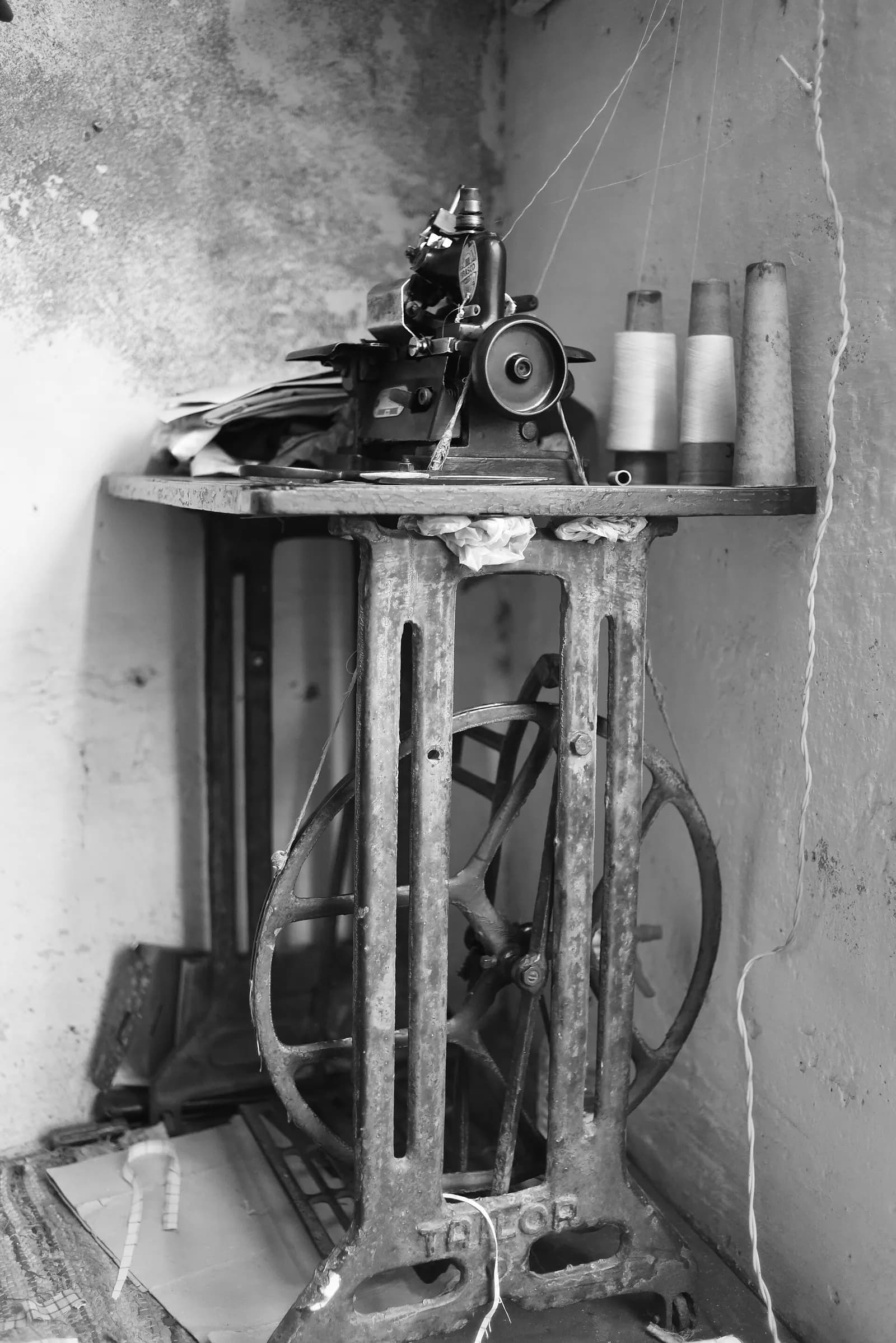 A tailor's treadle sewing machine with thread spools on the table in a small shop in Punjab