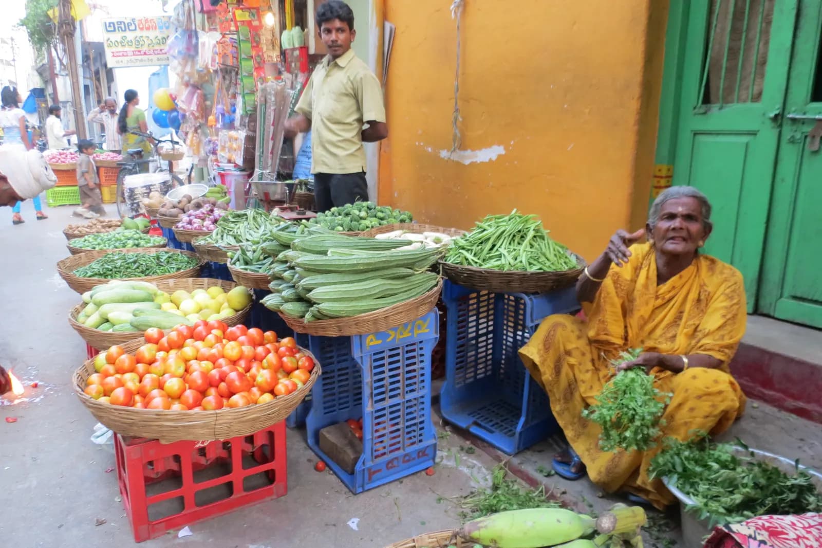 A woman selling vegetables from baskets and crates on a busy Hyderabad street