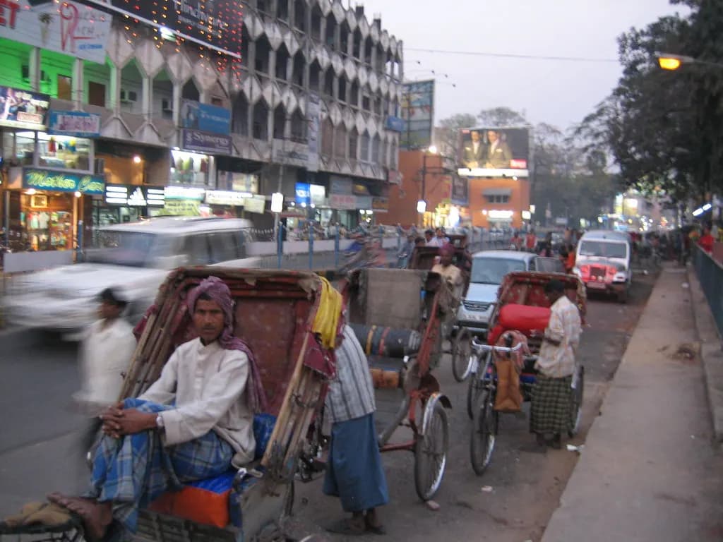 A Patna street with shopfronts on one side and cycle-rickshaws waiting at the kerb