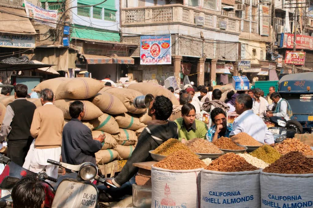 Dry-fruit traders with sacks of almonds and raisins in a crowded wholesale lane of Khari Baoli, Old Delhi