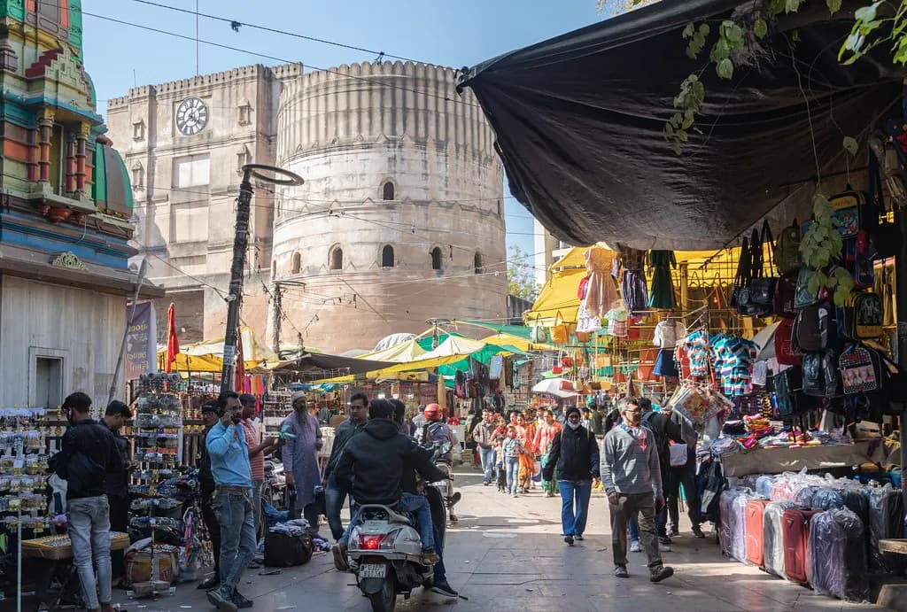 Market stalls selling bags, luggage and clothes under awnings near the Bhadra Fort tower in Ahmedabad's old city