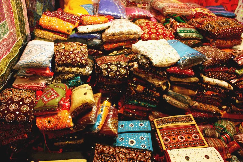 Piles of embroidered and mirror-work textiles and bags on sale at the Law Garden market in Ahmedabad