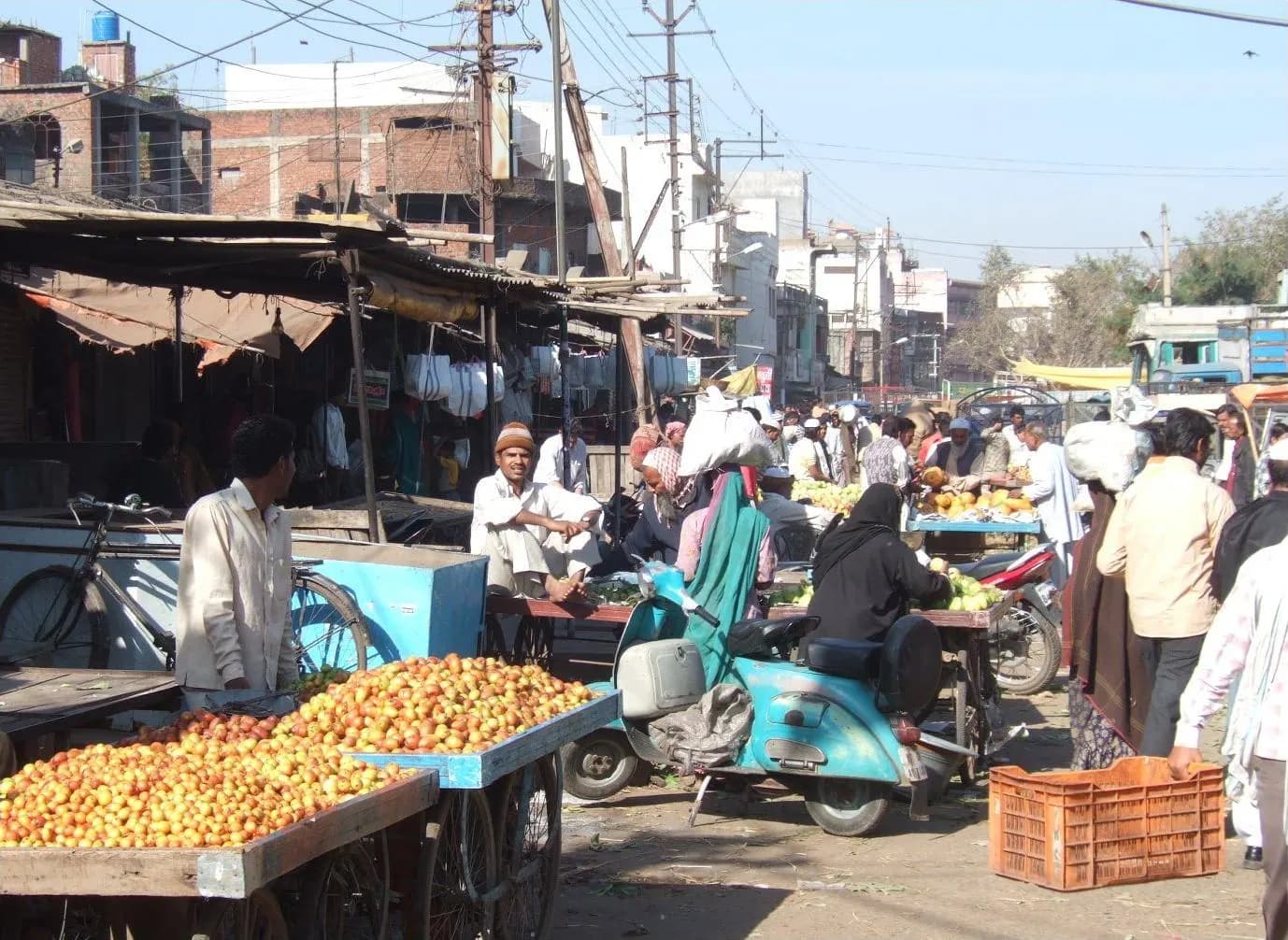 Fruit and vegetable carts along a busy market street in Bhopal with shops behind