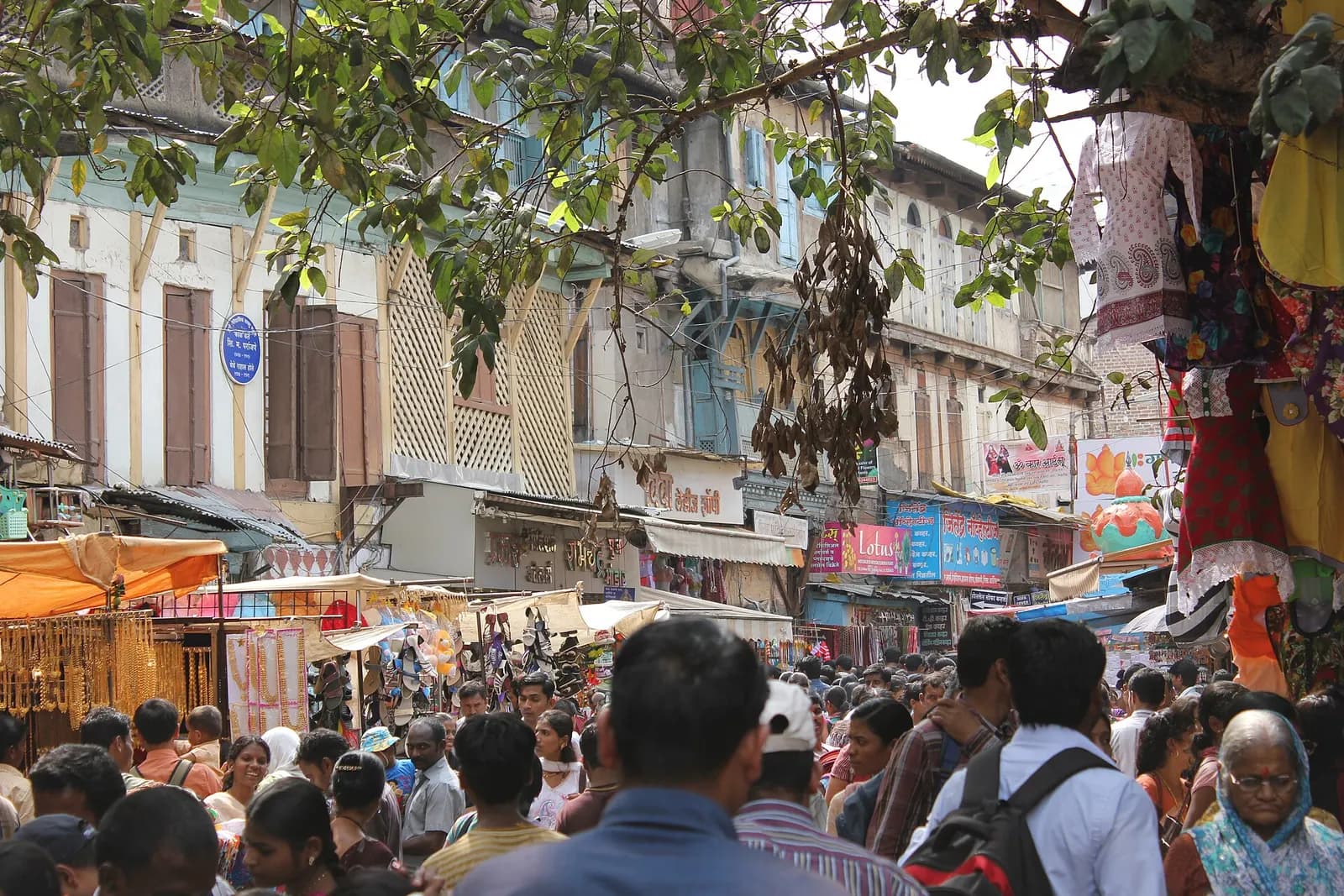 A crowded lane of small shops in Tulshibaug market, Pune, with stalls selling clothes and household goods
