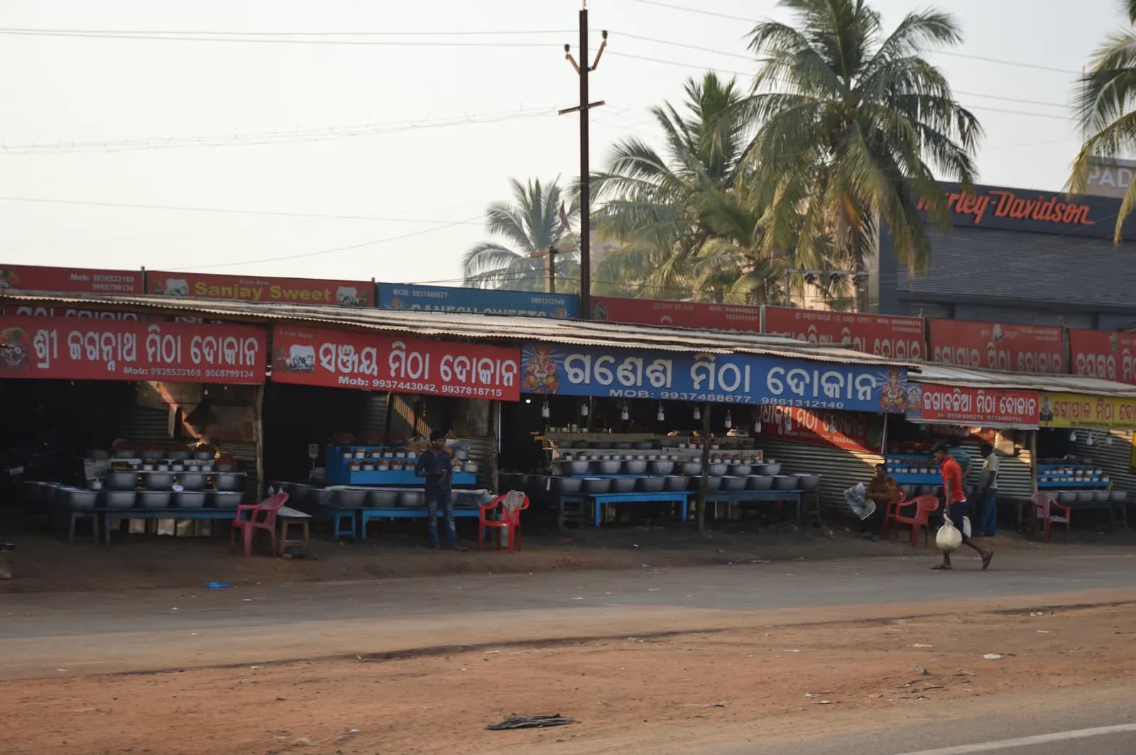 A row of roadside pickle and snack shops with Odia-language signboards at Pahal on NH 16 near Bhubaneswar
