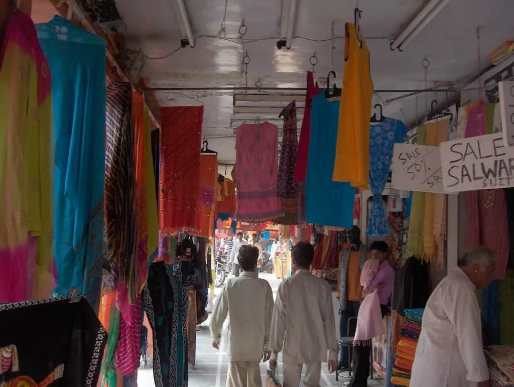 Shopfronts with fabrics and clothing along a market street in Jaipur's old city