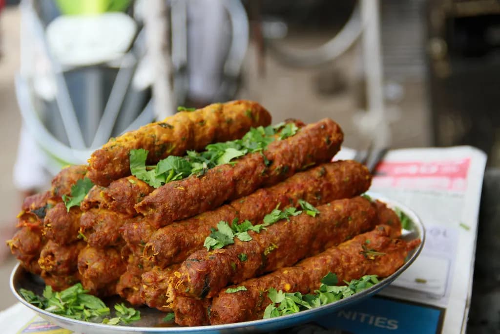 A plate of seekh kebabs garnished with coriander at a roadside eatery counter in Hyderabad