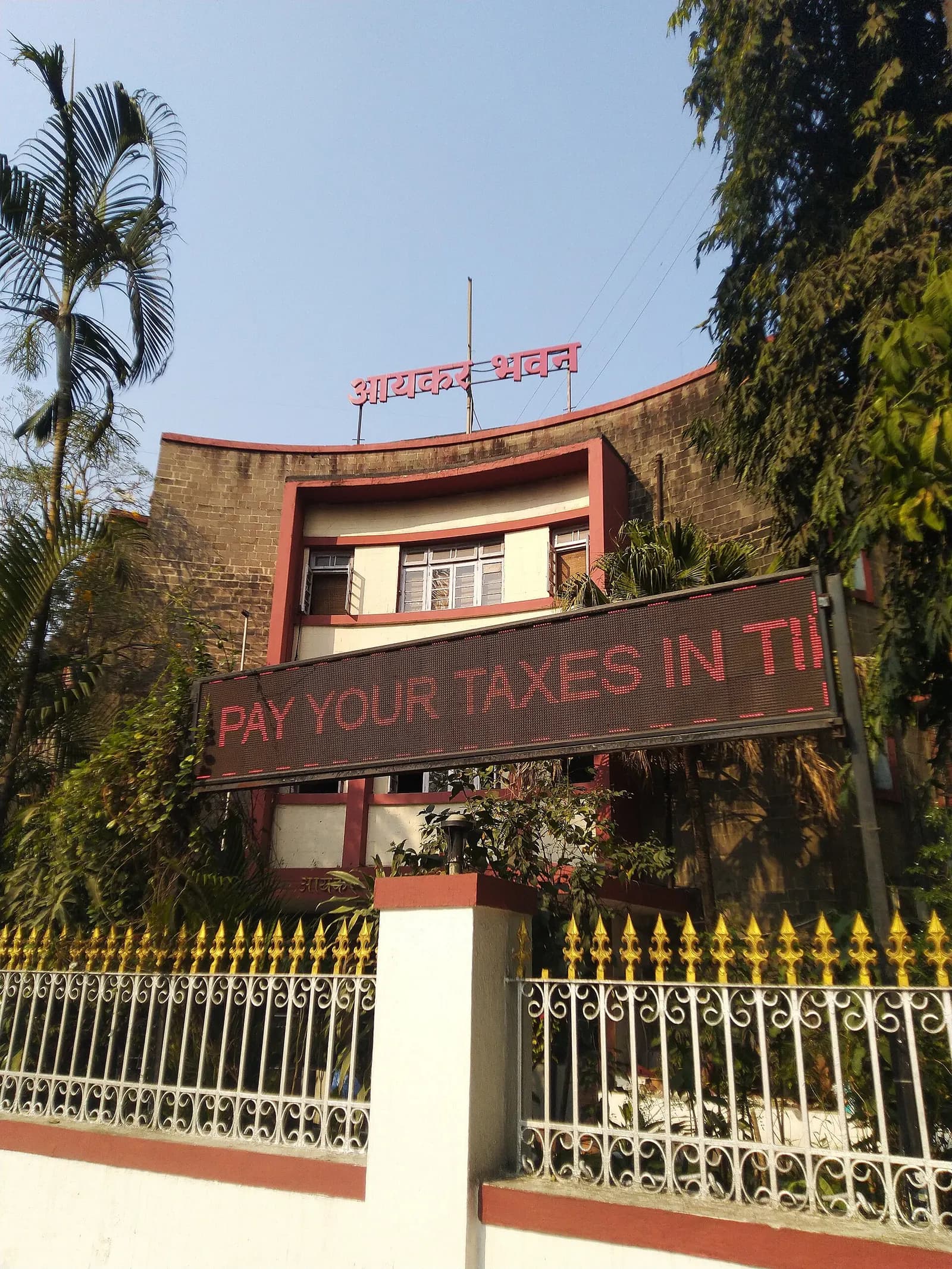 Aaykar Bhavan, the Income Tax Department building in Pune, with a 'Pay your taxes in time' banner on the gate