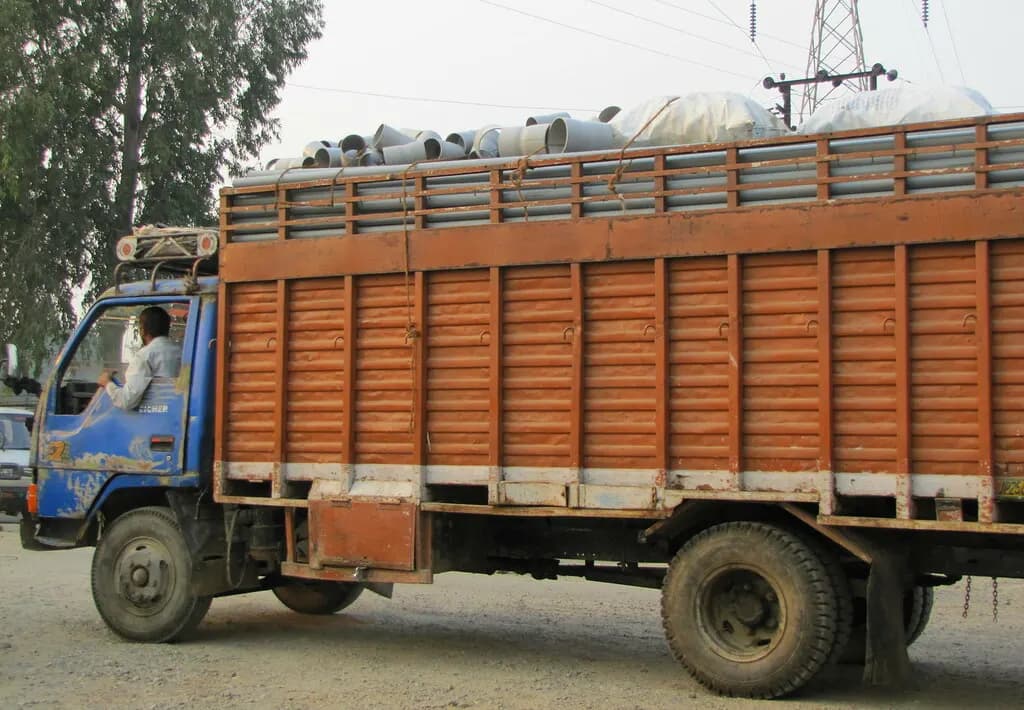 A loaded goods truck carrying pipes and sacks