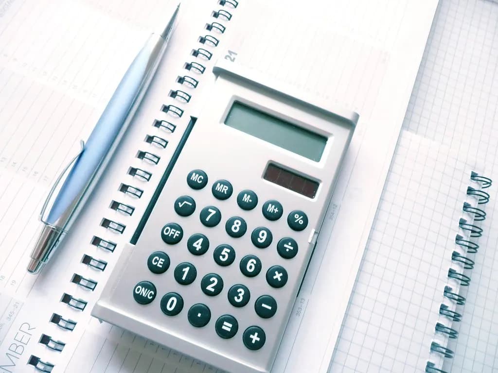 A calculator and pen resting on an open desk diary