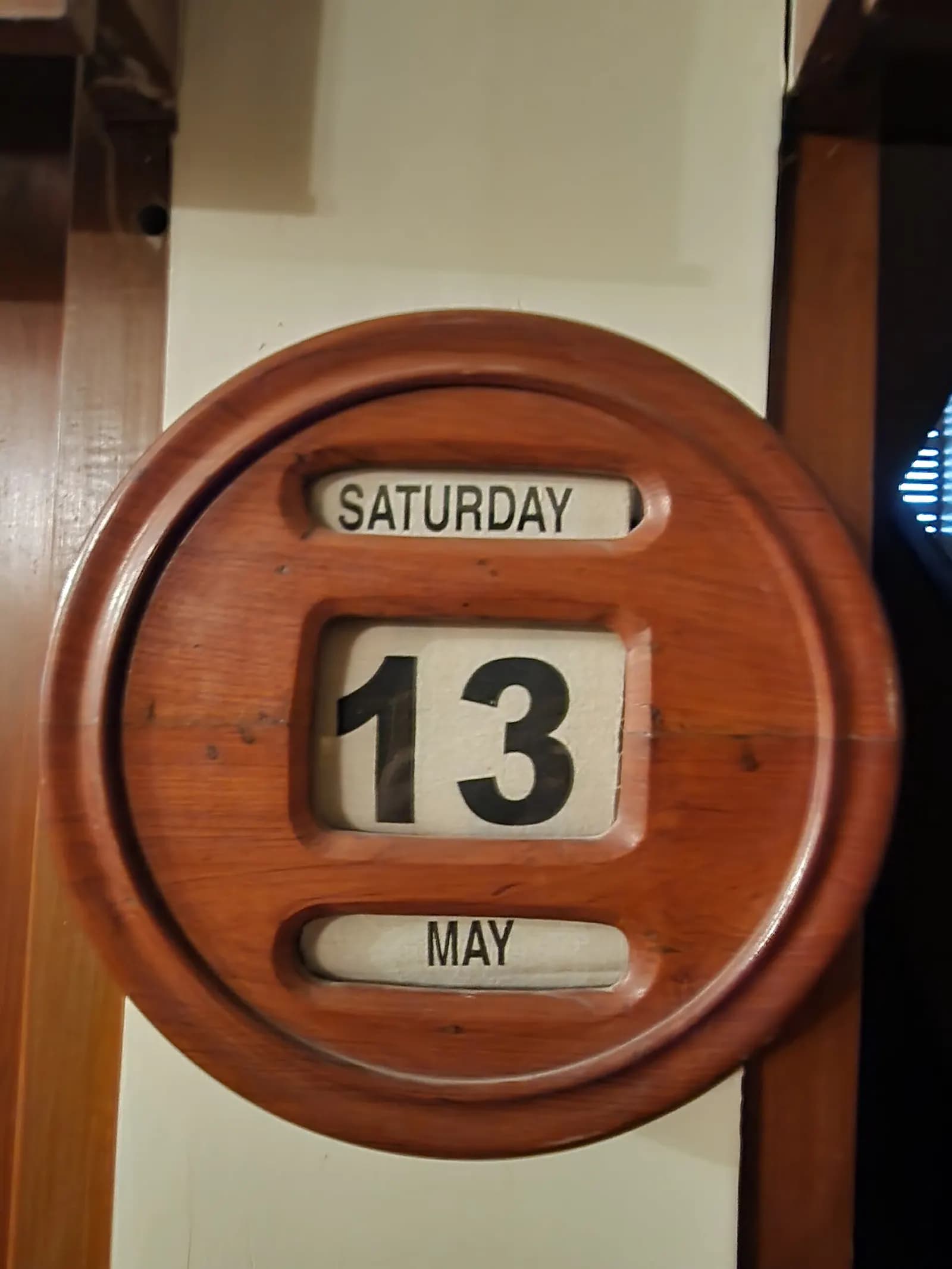 A wooden wall calendar with scrollable day, date and month strips